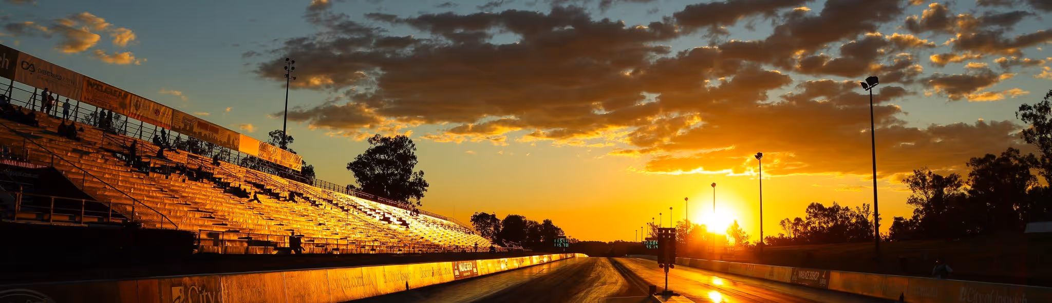 A young woman working in a machine shop. She is looking directly towards the camera, and is surrounded by men.