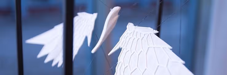 A young woman working in a machine shop. She is looking directly towards the camera, and is surrounded by men.