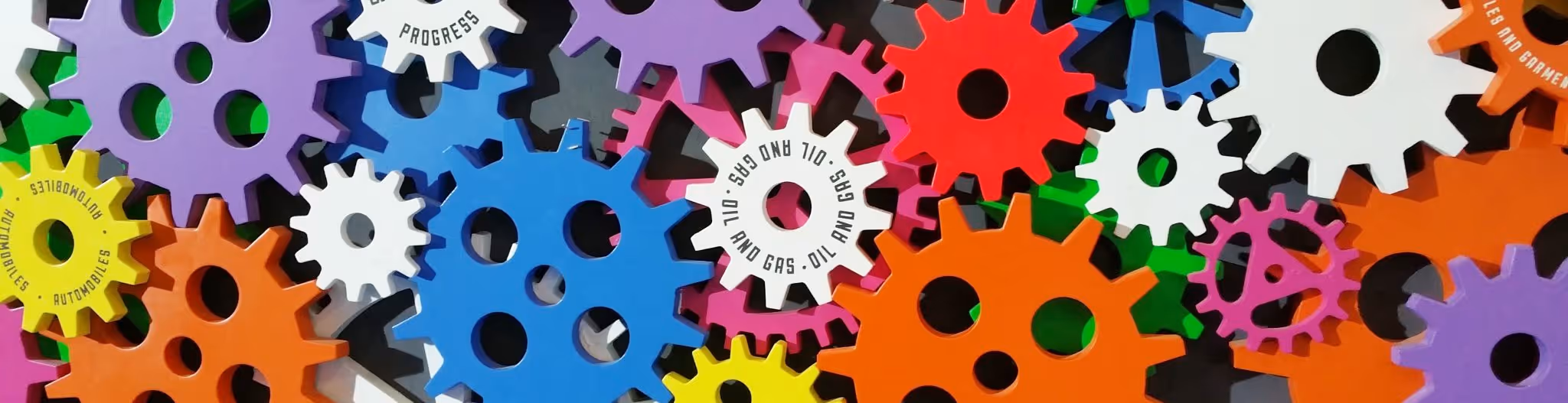 A young woman working in a machine shop. She is looking directly towards the camera, and is surrounded by men.