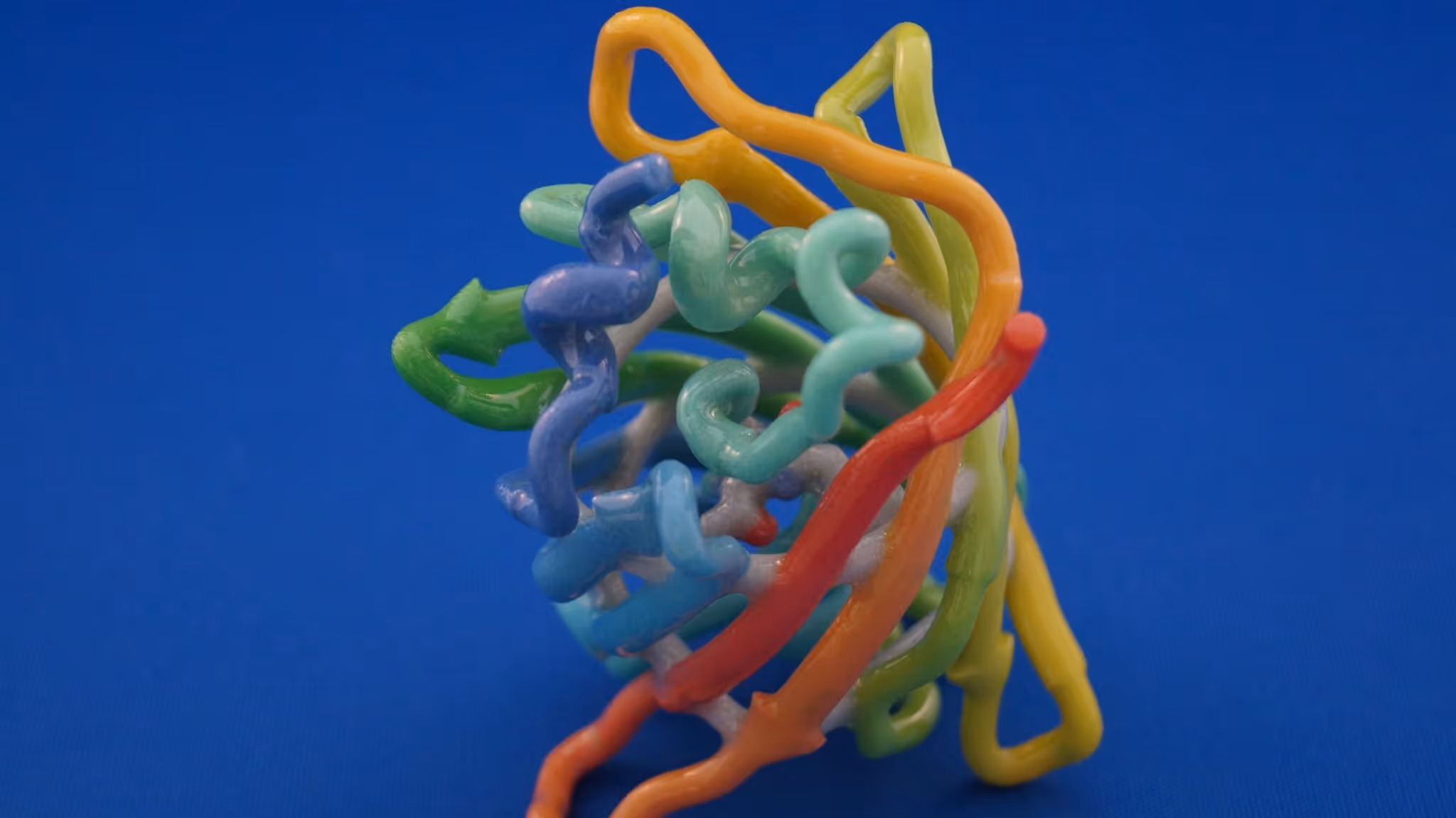 A young woman working in a machine shop. She is looking directly towards the camera, and is surrounded by men.