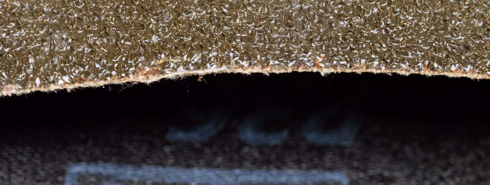 A young woman working in a machine shop. She is looking directly towards the camera, and is surrounded by men.