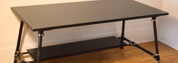 A young woman working in a machine shop. She is looking directly towards the camera, and is surrounded by men.