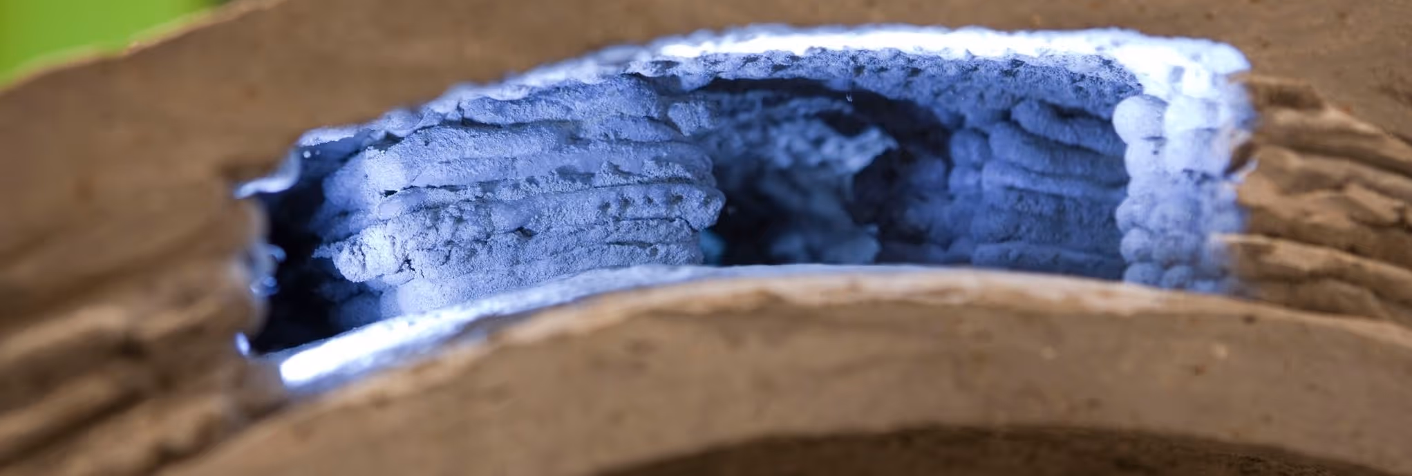 A young woman working in a machine shop. She is looking directly towards the camera, and is surrounded by men.