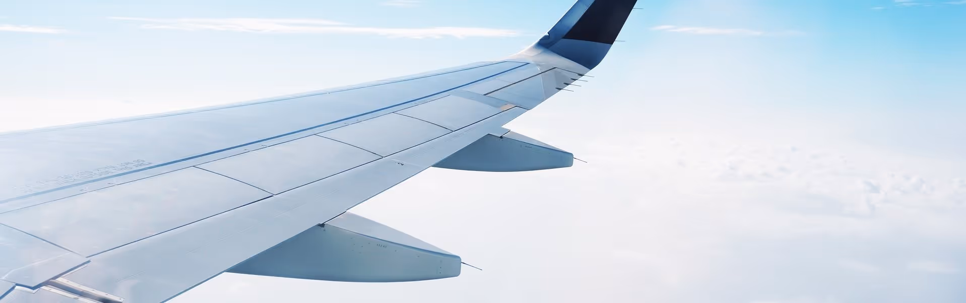 A young woman working in a machine shop. She is looking directly towards the camera, and is surrounded by men.