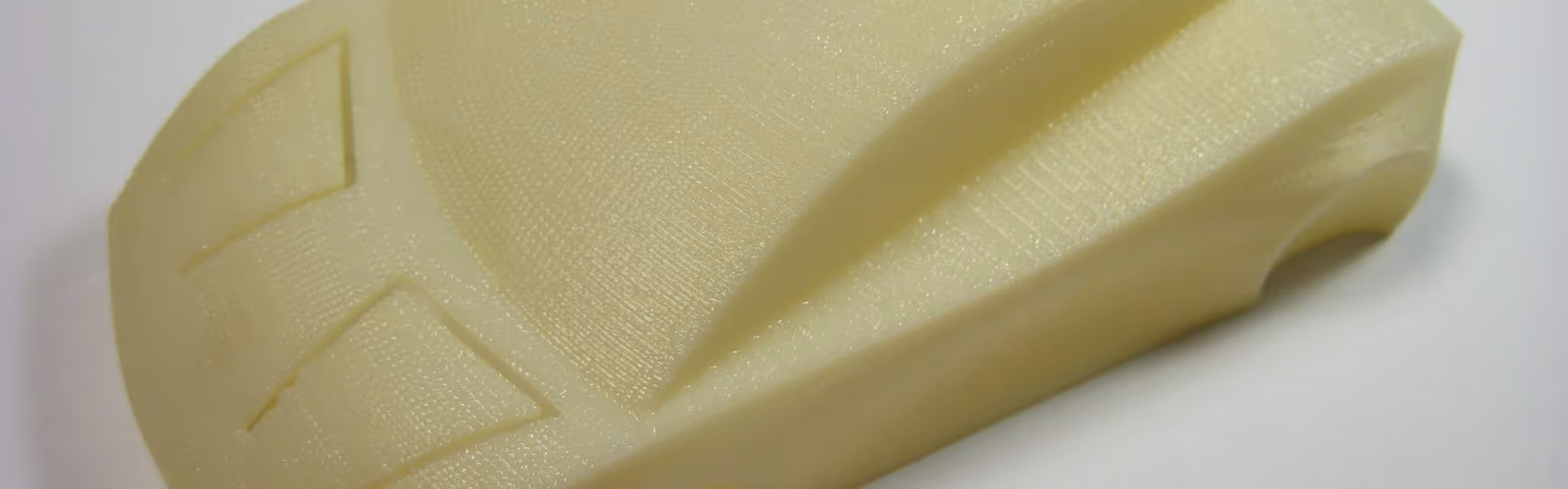 A young woman working in a machine shop. She is looking directly towards the camera, and is surrounded by men.