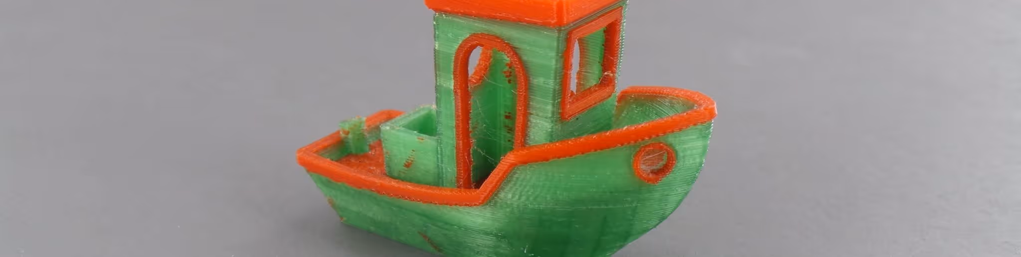 A young woman working in a machine shop. She is looking directly towards the camera, and is surrounded by men.