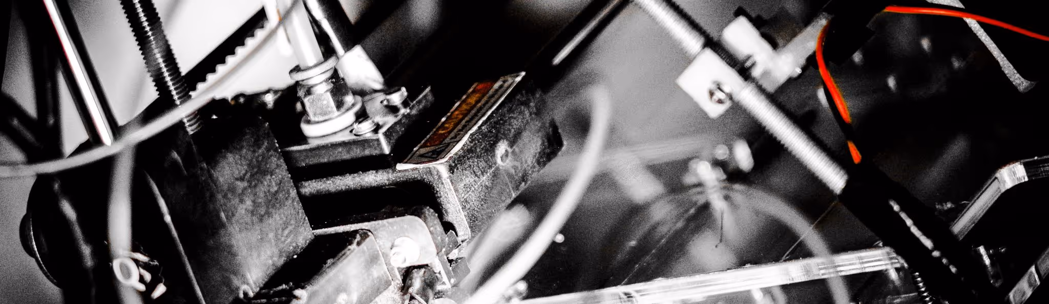 A young woman working in a machine shop. She is looking directly towards the camera, and is surrounded by men.