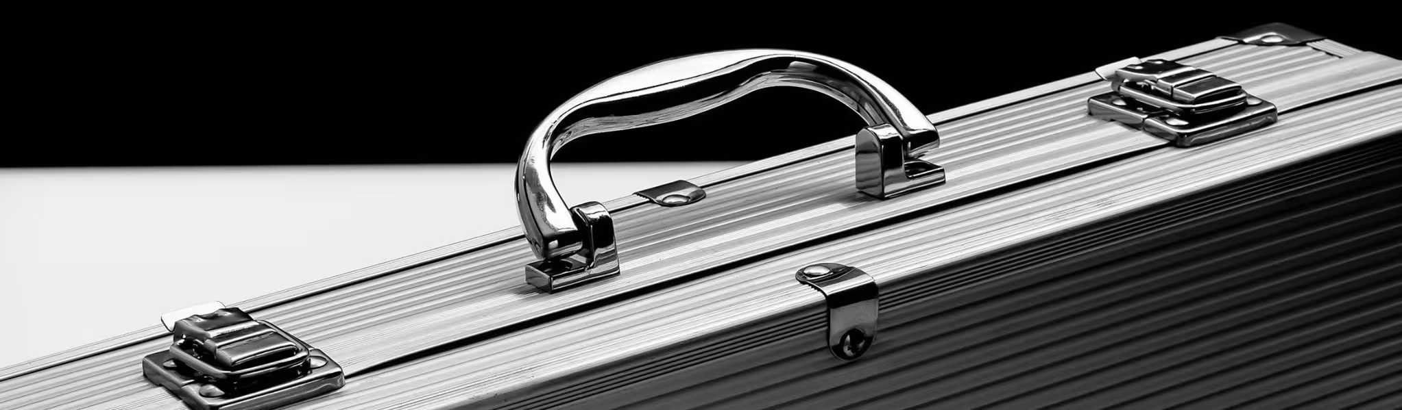 A young woman working in a machine shop. She is looking directly towards the camera, and is surrounded by men.