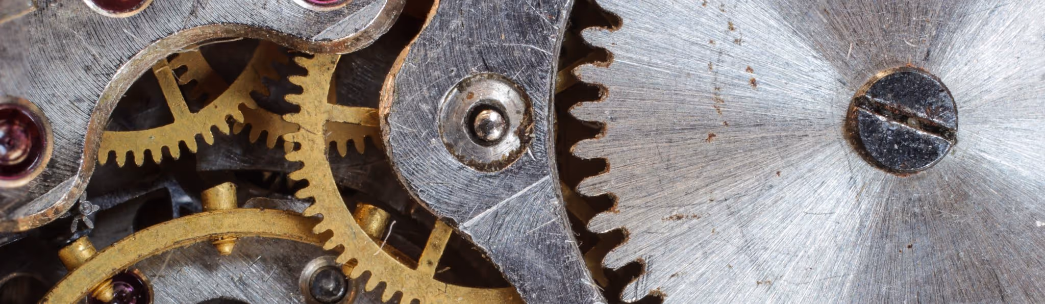 A young woman working in a machine shop. She is looking directly towards the camera, and is surrounded by men.
