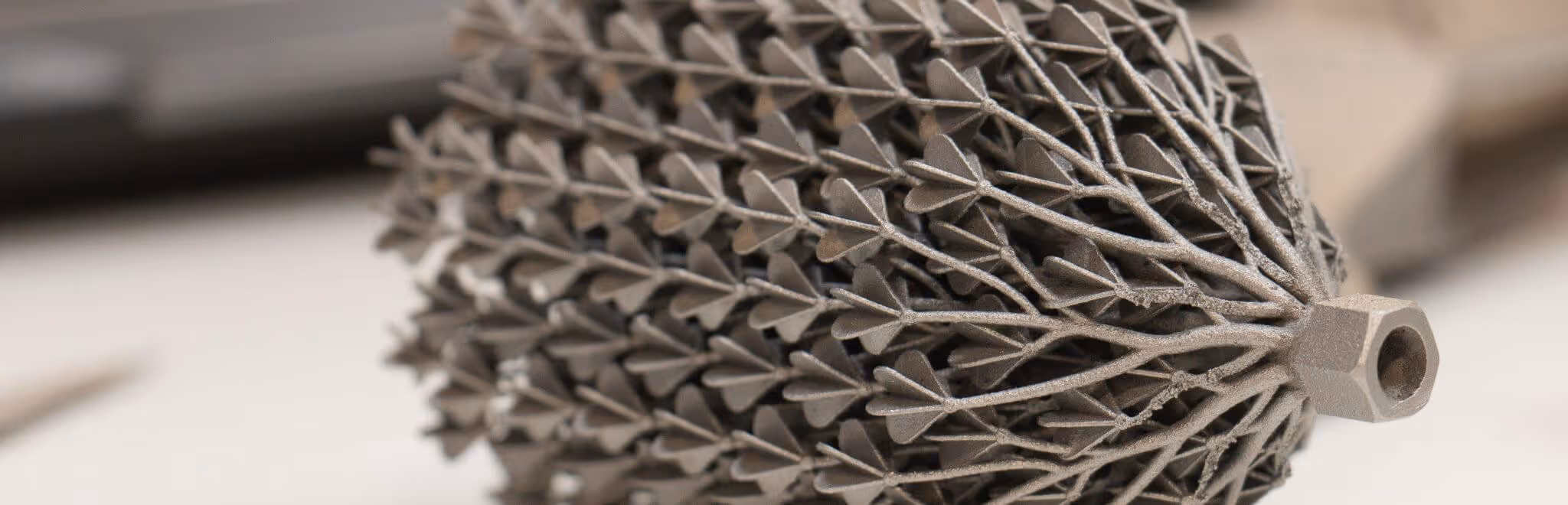 A young woman working in a machine shop. She is looking directly towards the camera, and is surrounded by men.