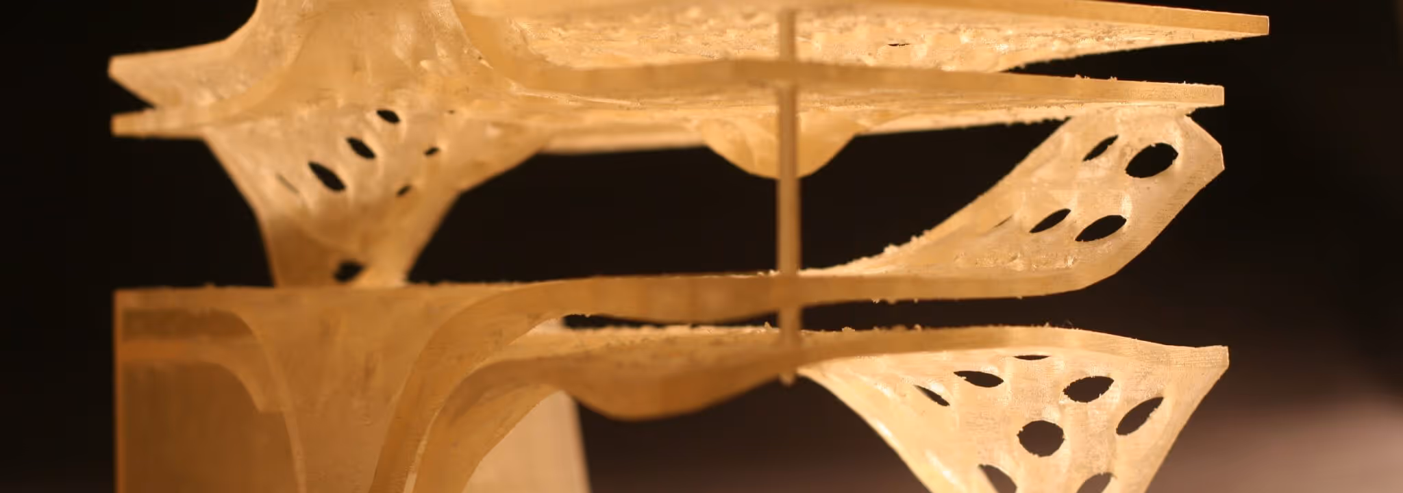 A young woman working in a machine shop. She is looking directly towards the camera, and is surrounded by men.