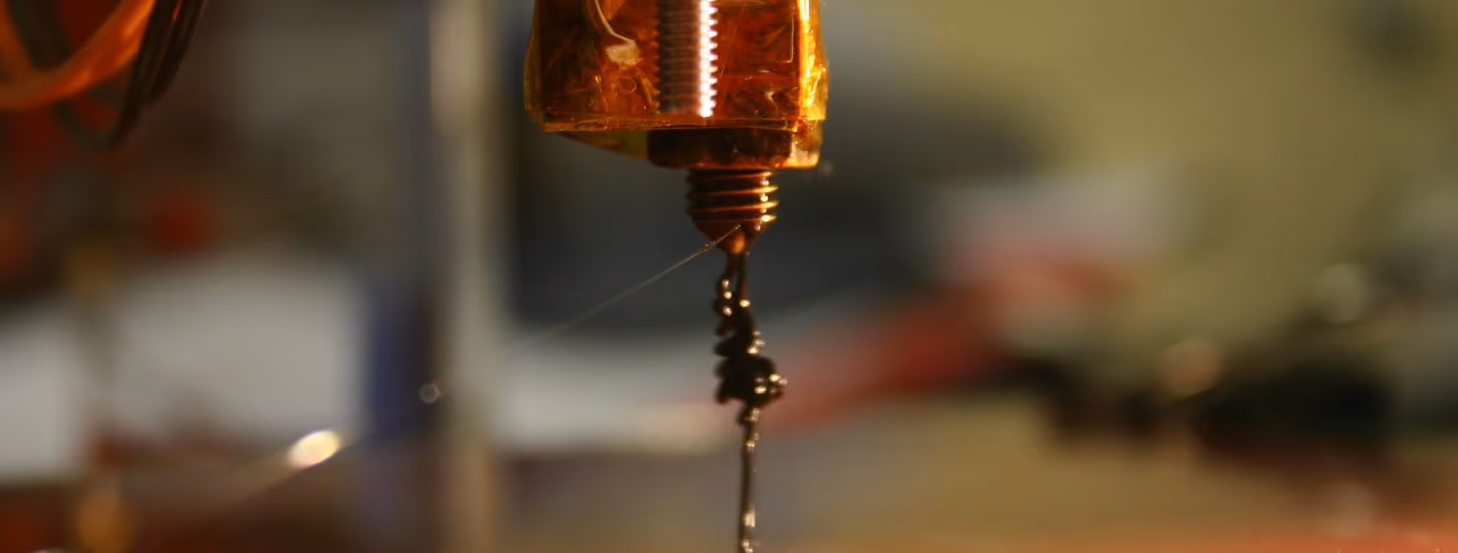 A young woman working in a machine shop. She is looking directly towards the camera, and is surrounded by men.