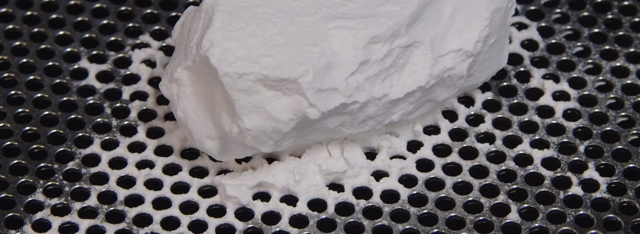 A young woman working in a machine shop. She is looking directly towards the camera, and is surrounded by men.