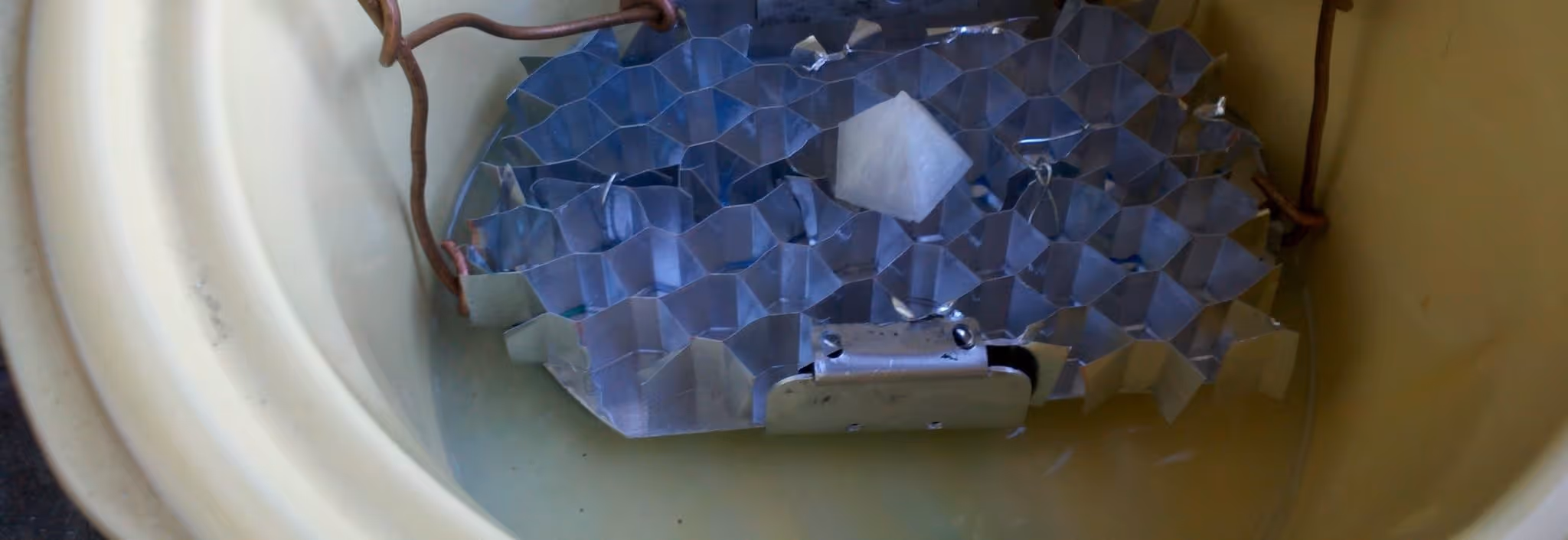 A young woman working in a machine shop. She is looking directly towards the camera, and is surrounded by men.