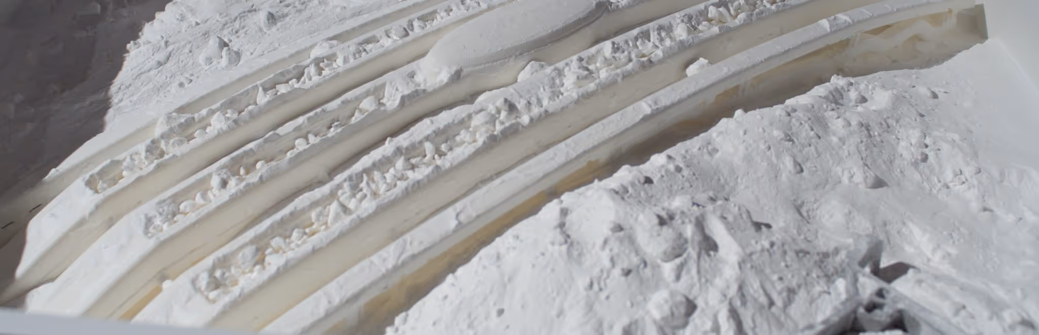 A young woman working in a machine shop. She is looking directly towards the camera, and is surrounded by men.