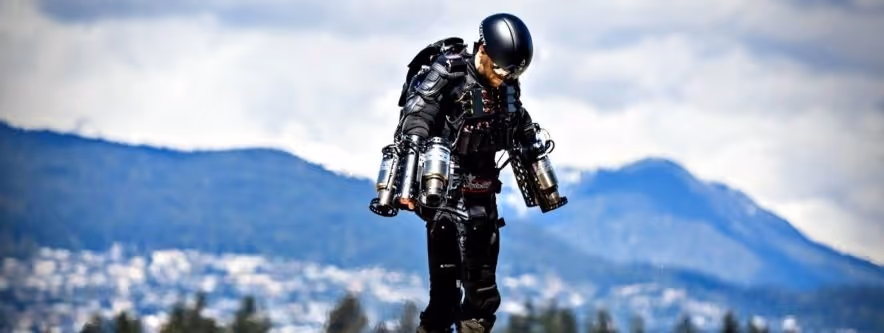 A young woman working in a machine shop. She is looking directly towards the camera, and is surrounded by men.