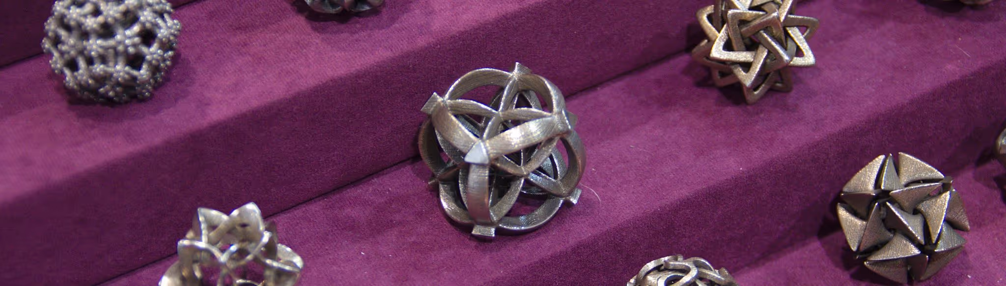 A young woman working in a machine shop. She is looking directly towards the camera, and is surrounded by men.