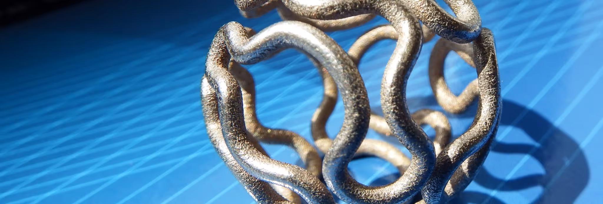 A young woman working in a machine shop. She is looking directly towards the camera, and is surrounded by men.
