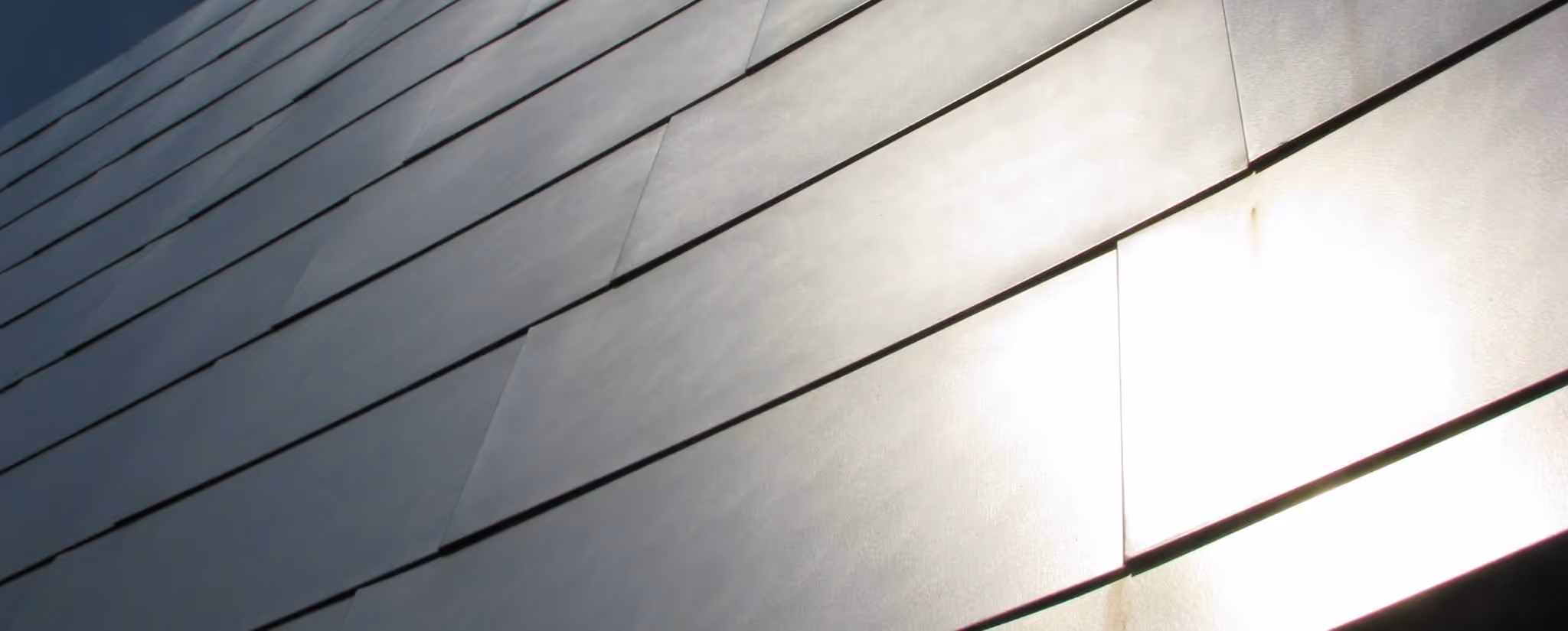 A young woman working in a machine shop. She is looking directly towards the camera, and is surrounded by men.