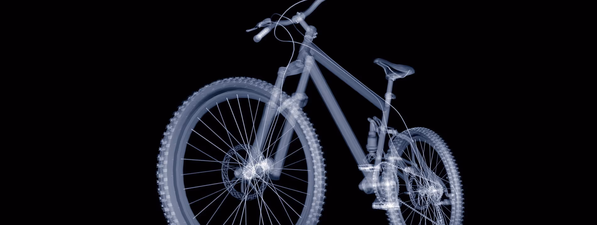A young woman working in a machine shop. She is looking directly towards the camera, and is surrounded by men.