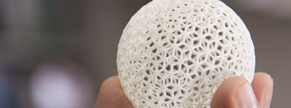 A young woman working in a machine shop. She is looking directly towards the camera, and is surrounded by men.