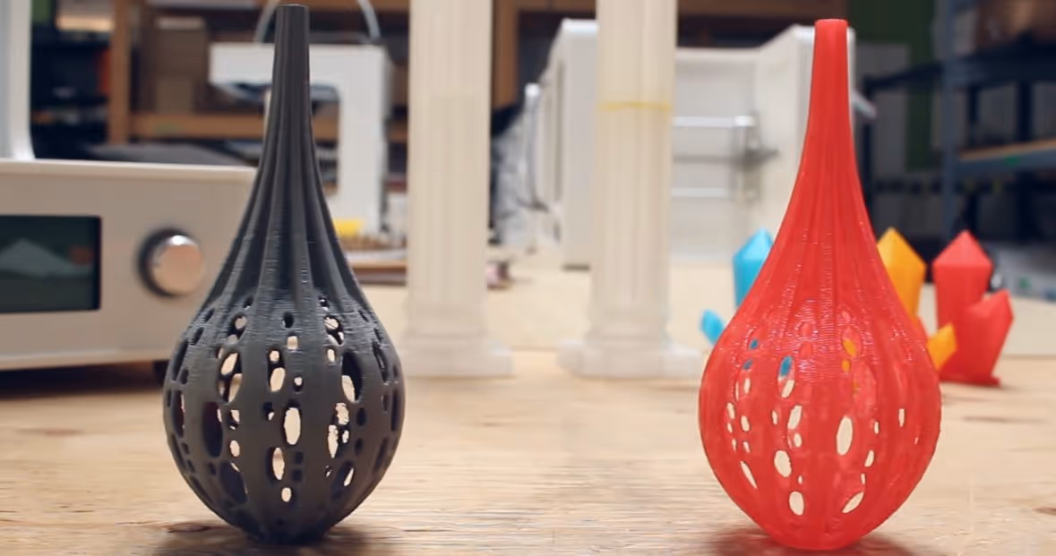 A young woman working in a machine shop. She is looking directly towards the camera, and is surrounded by men.