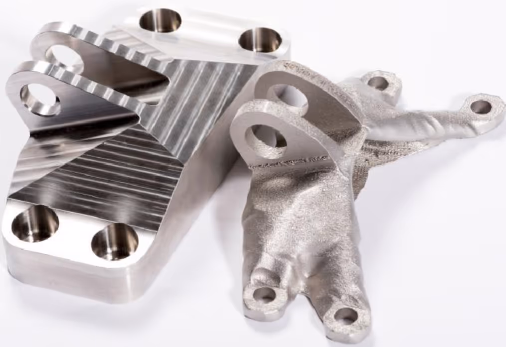 A young woman working in a machine shop. She is looking directly towards the camera, and is surrounded by men.