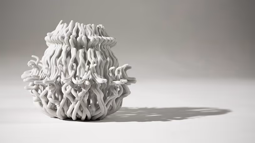 A young woman working in a machine shop. She is looking directly towards the camera, and is surrounded by men.