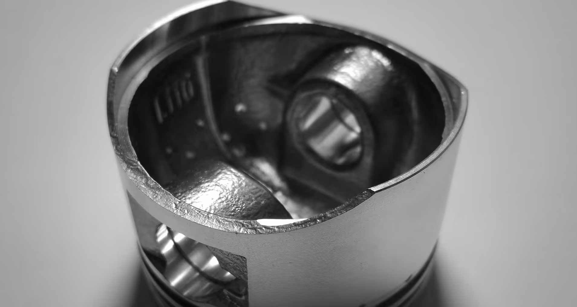 A young woman working in a machine shop. She is looking directly towards the camera, and is surrounded by men.