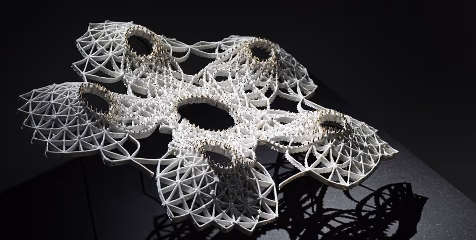 A young woman working in a machine shop. She is looking directly towards the camera, and is surrounded by men.