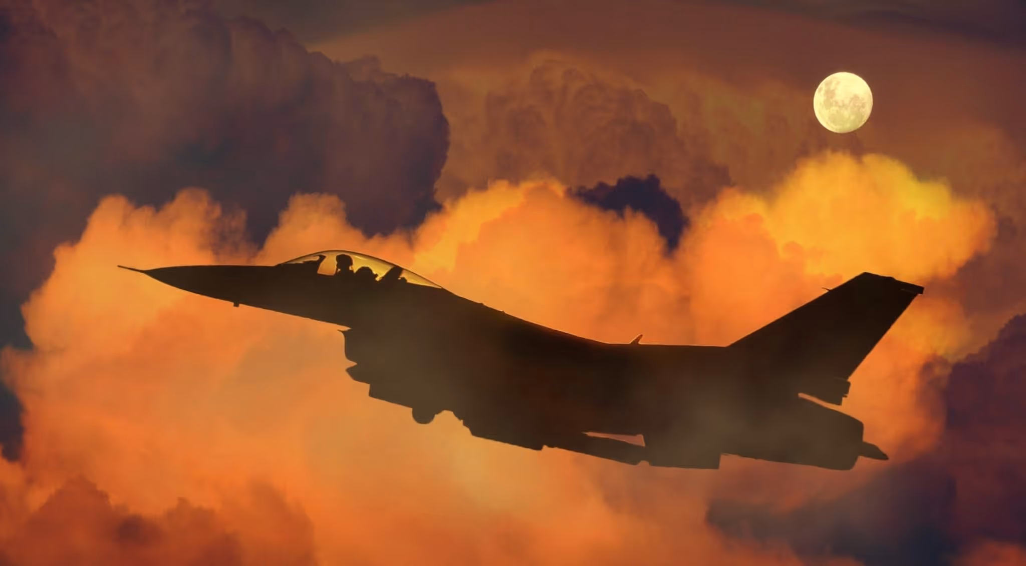 A young woman working in a machine shop. She is looking directly towards the camera, and is surrounded by men.