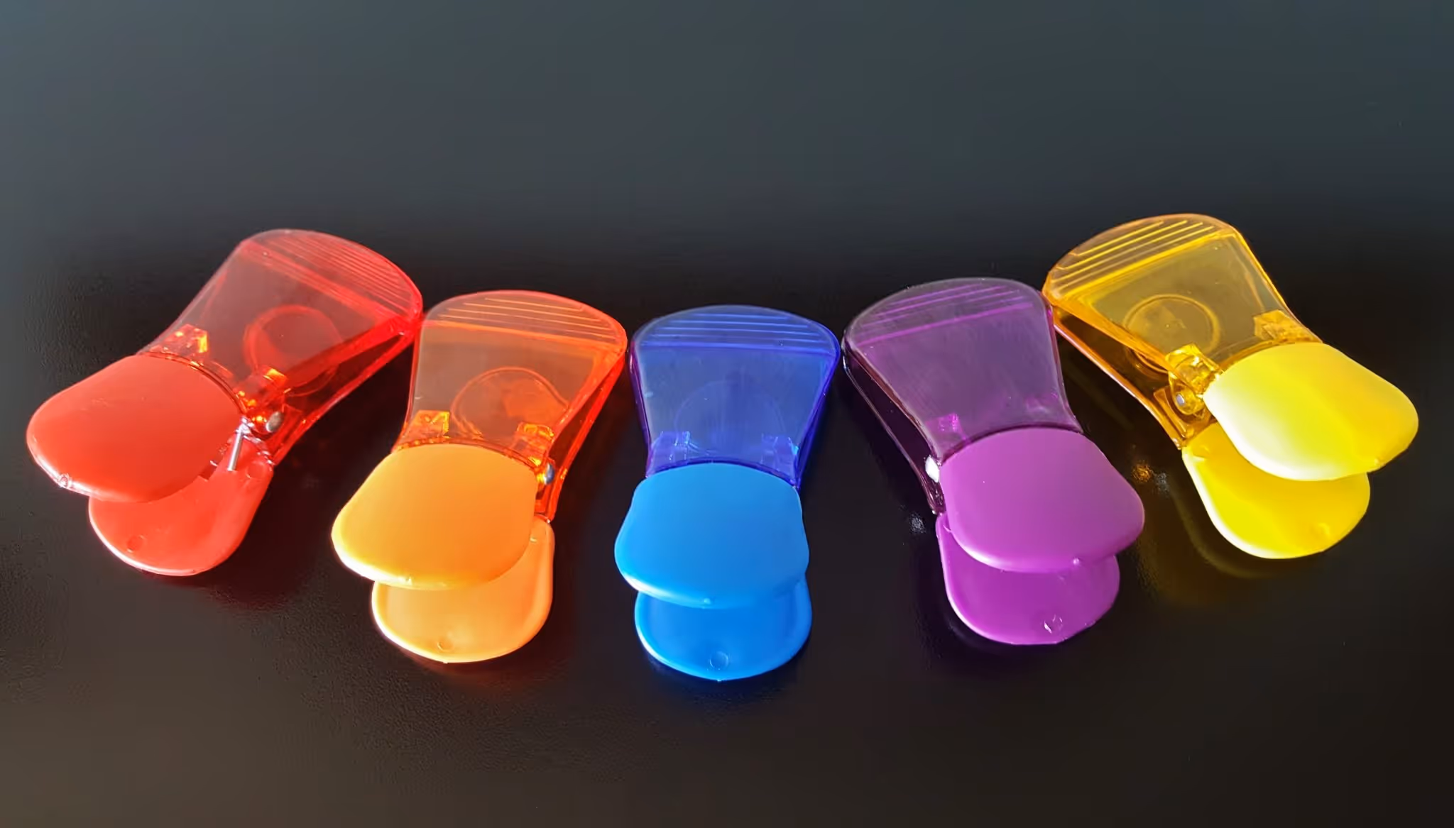 A young woman working in a machine shop. She is looking directly towards the camera, and is surrounded by men.