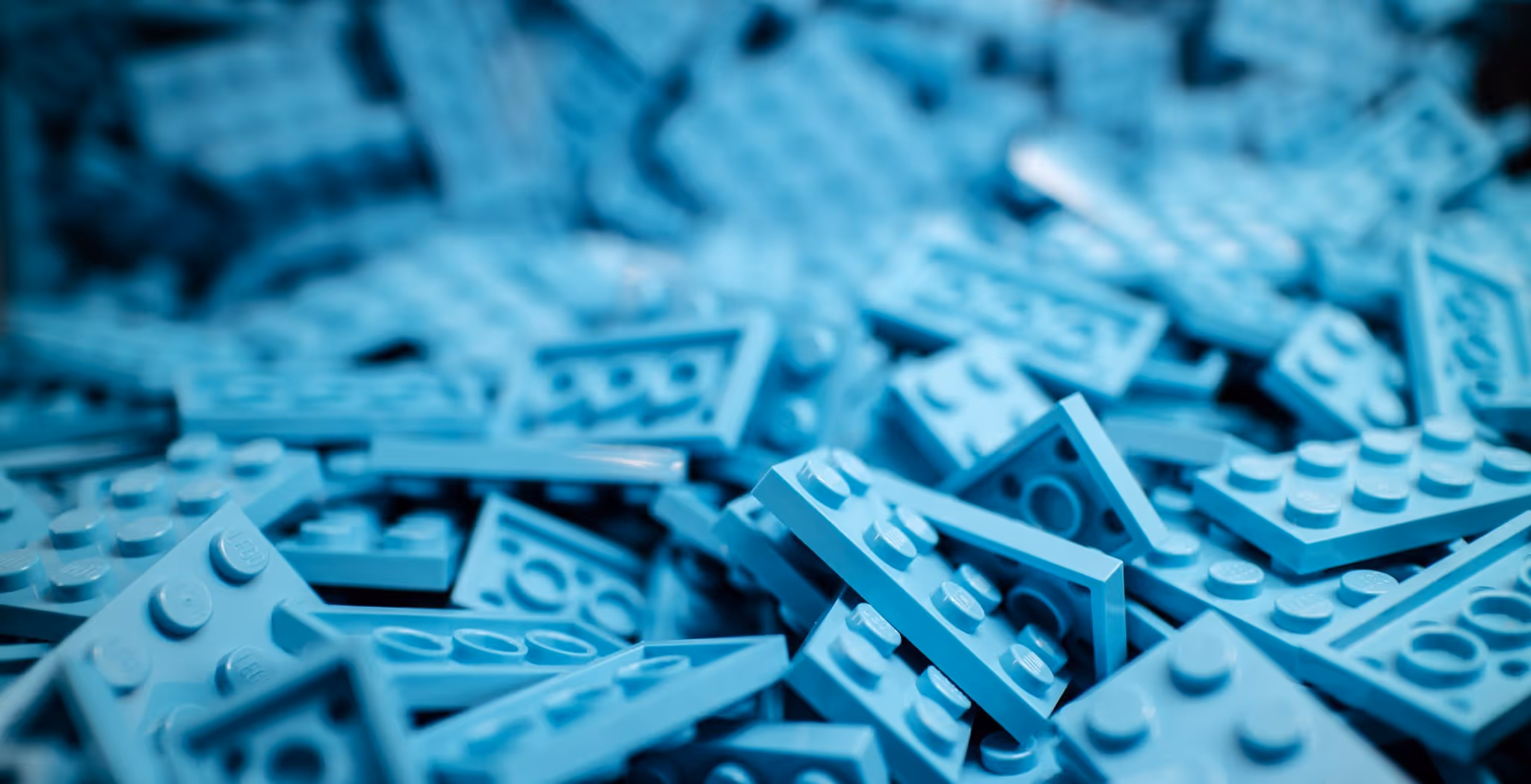 A young woman working in a machine shop. She is looking directly towards the camera, and is surrounded by men.