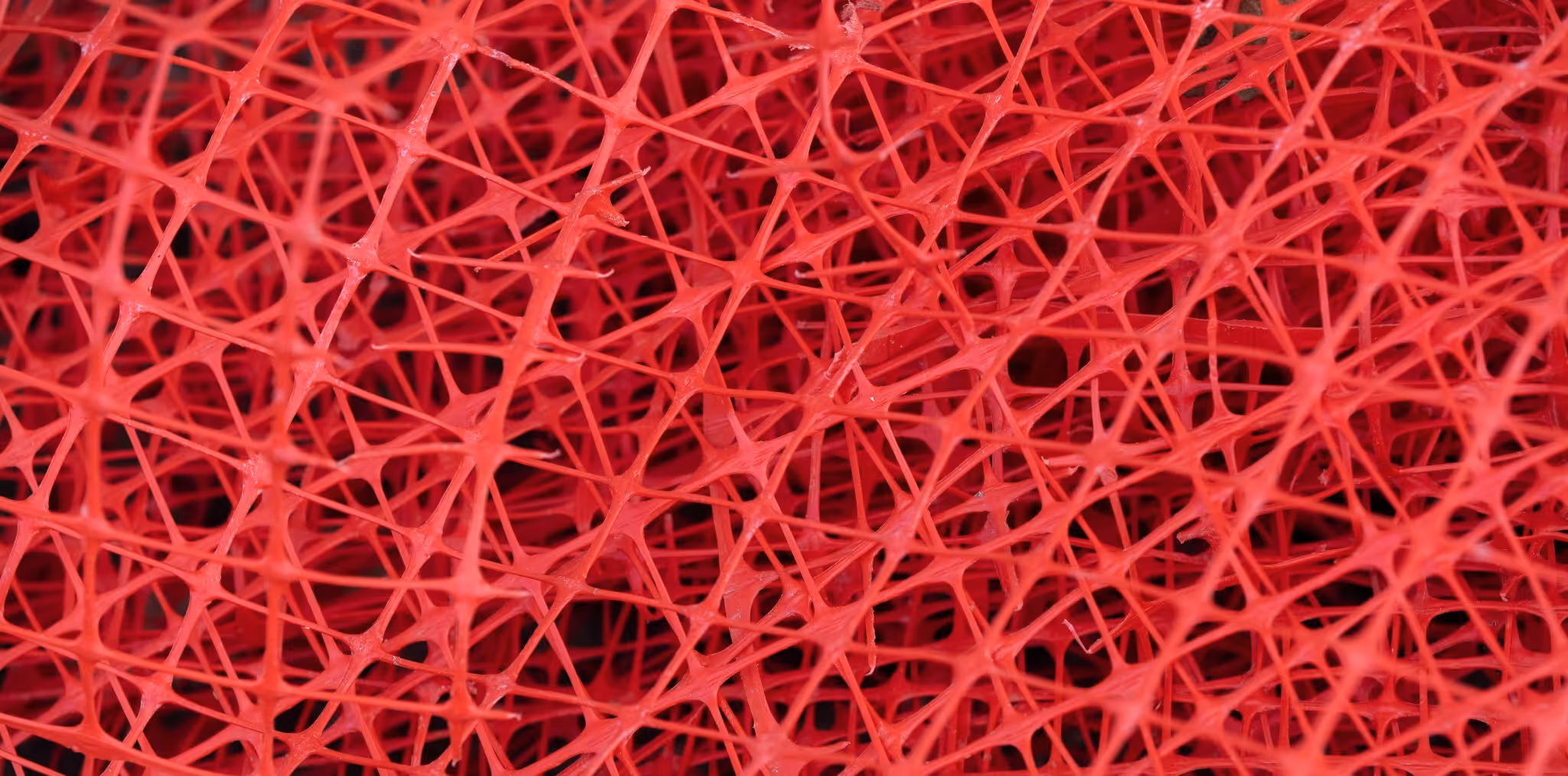 A young woman working in a machine shop. She is looking directly towards the camera, and is surrounded by men.