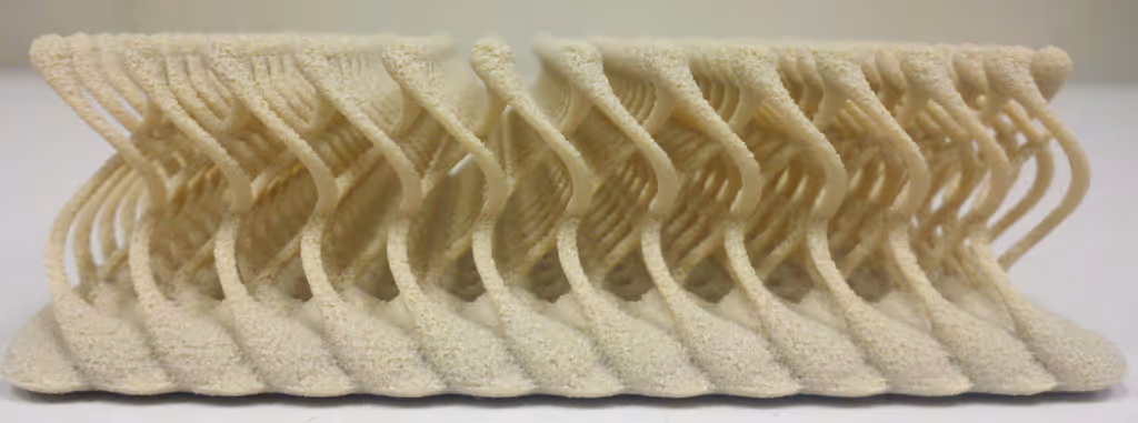 A young woman working in a machine shop. She is looking directly towards the camera, and is surrounded by men.