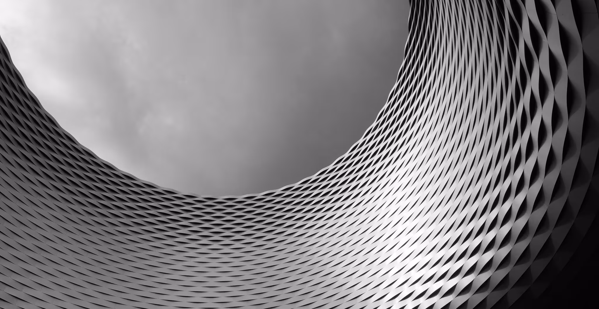 A young woman working in a machine shop. She is looking directly towards the camera, and is surrounded by men.