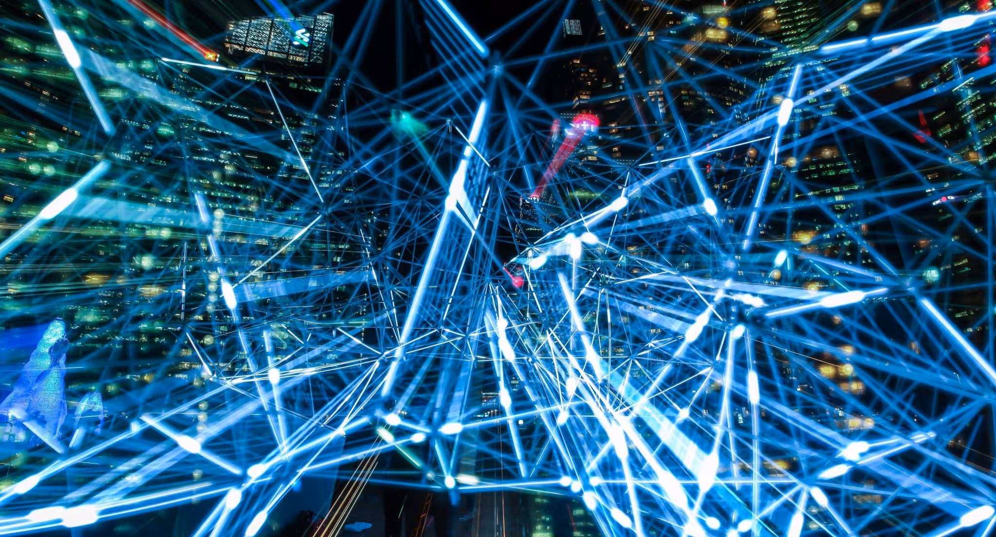 A young woman working in a machine shop. She is looking directly towards the camera, and is surrounded by men.