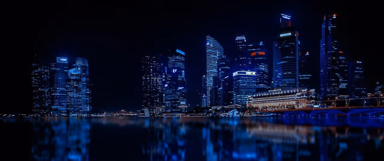 A young woman working in a machine shop. She is looking directly towards the camera, and is surrounded by men.