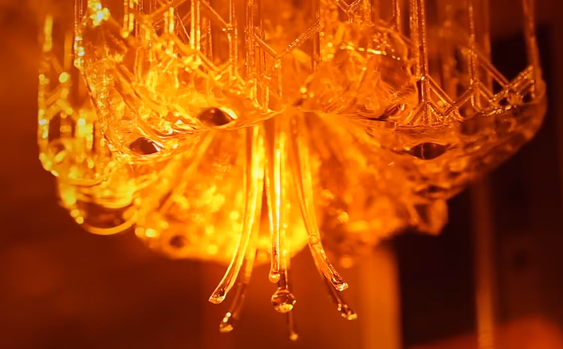 A young woman working in a machine shop. She is looking directly towards the camera, and is surrounded by men.