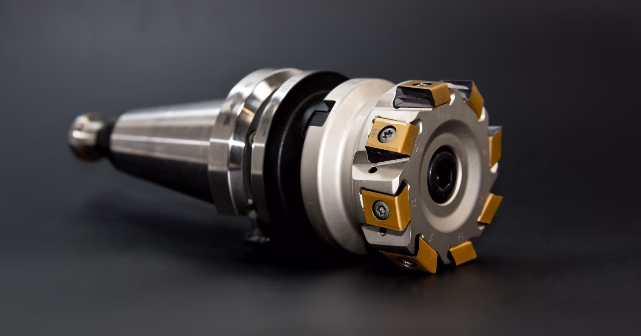 A young woman working in a machine shop. She is looking directly towards the camera, and is surrounded by men.