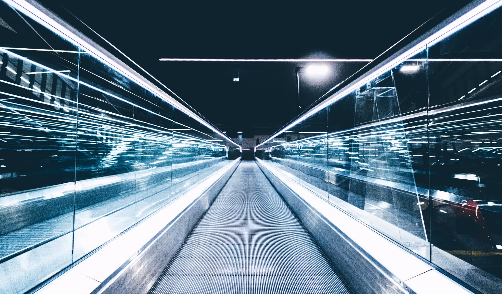 A young woman working in a machine shop. She is looking directly towards the camera, and is surrounded by men.