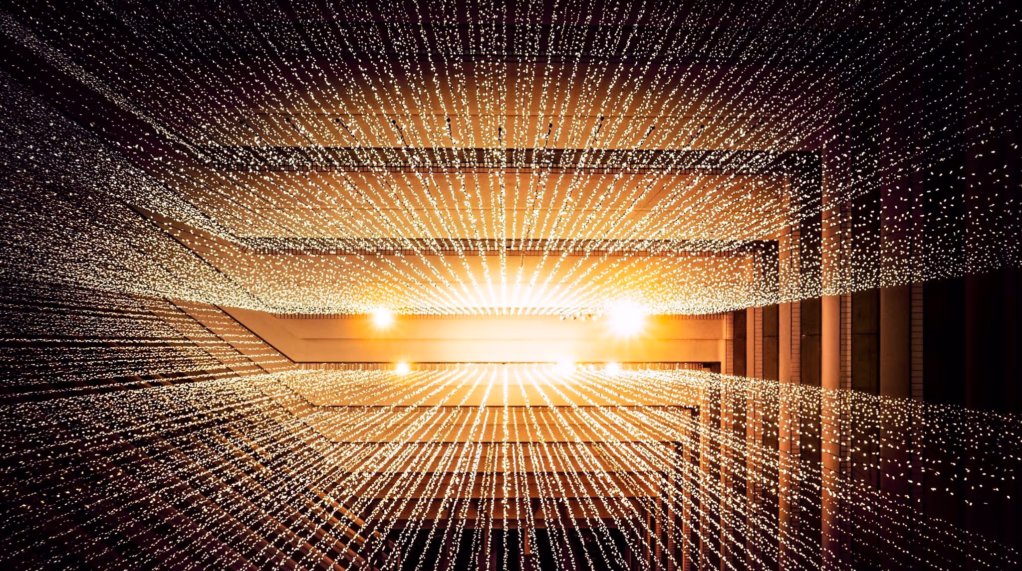 A young woman working in a machine shop. She is looking directly towards the camera, and is surrounded by men.