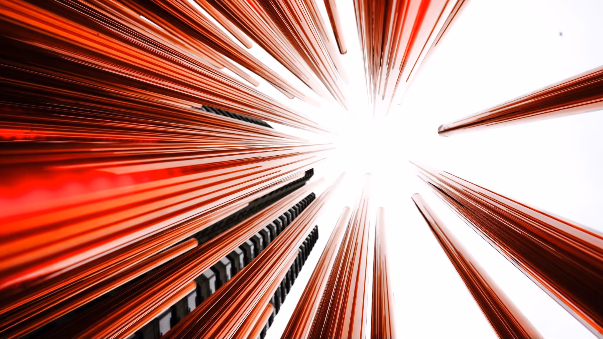 A young woman working in a machine shop. She is looking directly towards the camera, and is surrounded by men.