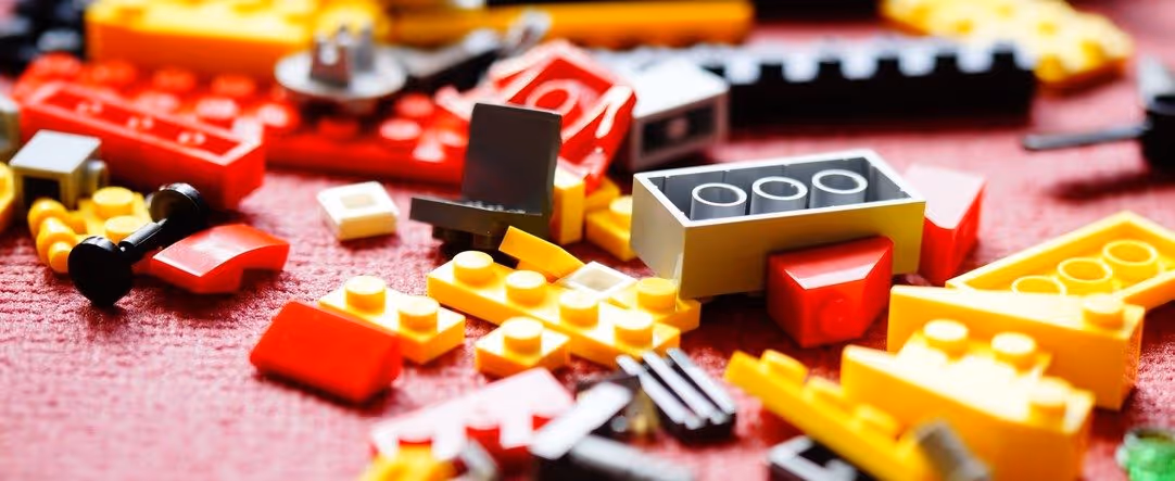 A young woman working in a machine shop. She is looking directly towards the camera, and is surrounded by men.