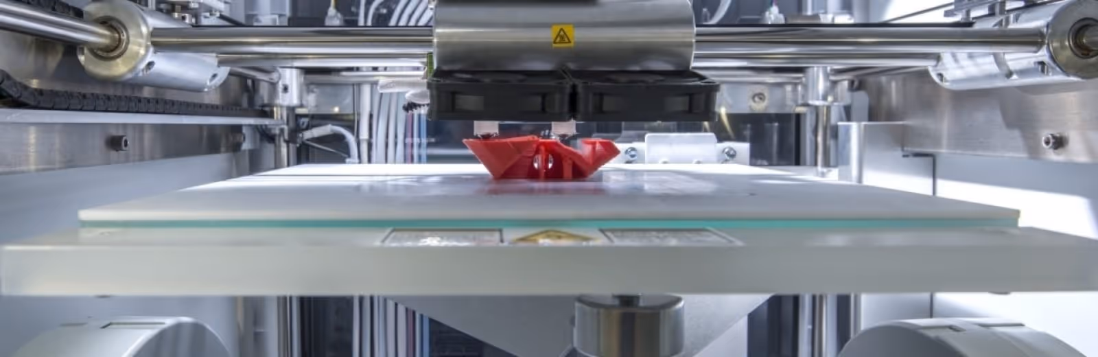 A young woman working in a machine shop. She is looking directly towards the camera, and is surrounded by men.
