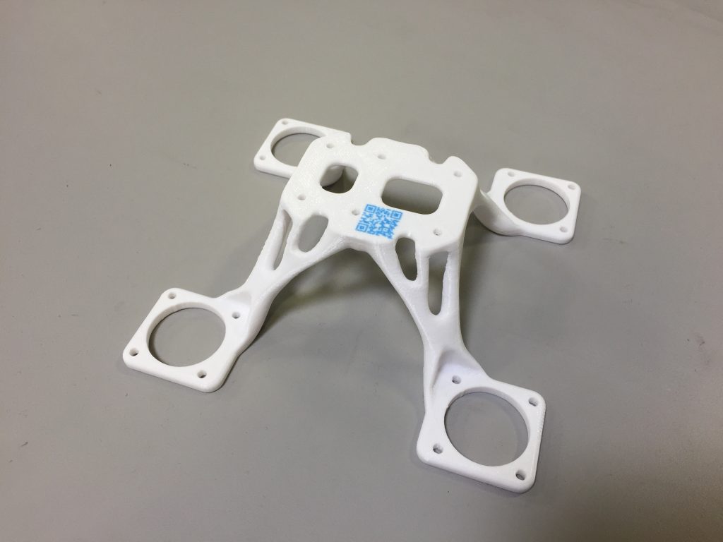 A white 3D printed part with a QR code 