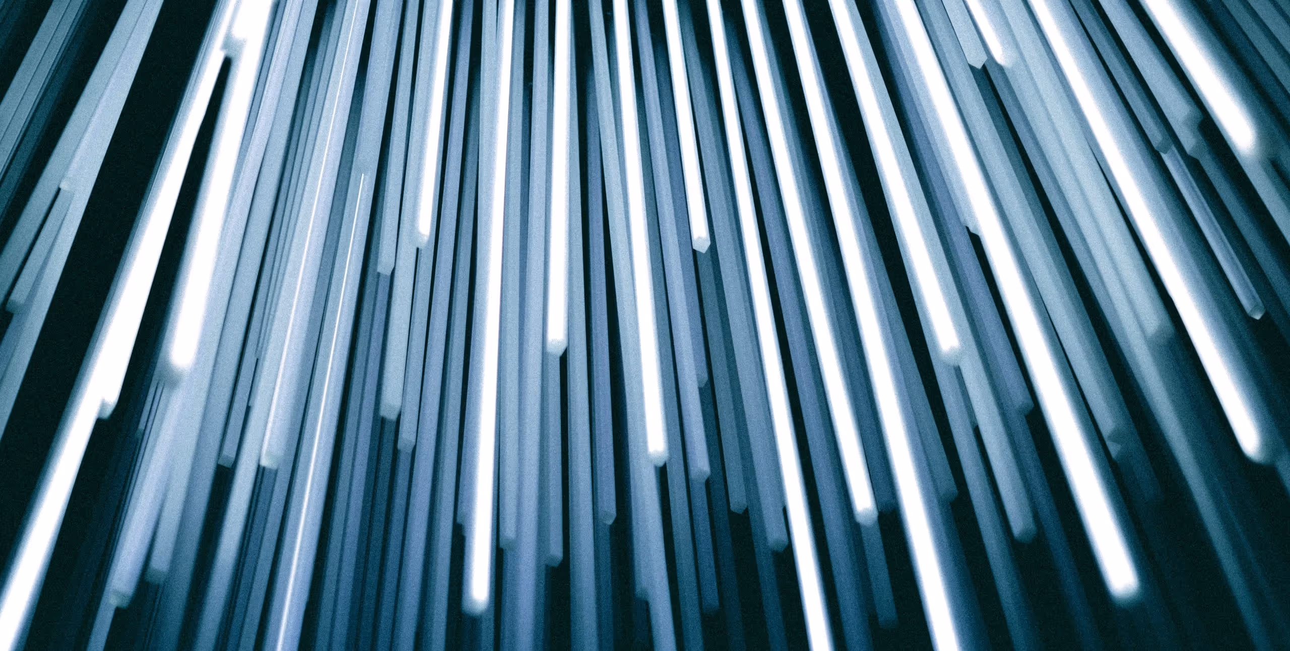 A young woman working in a machine shop. She is looking directly towards the camera, and is surrounded by men.