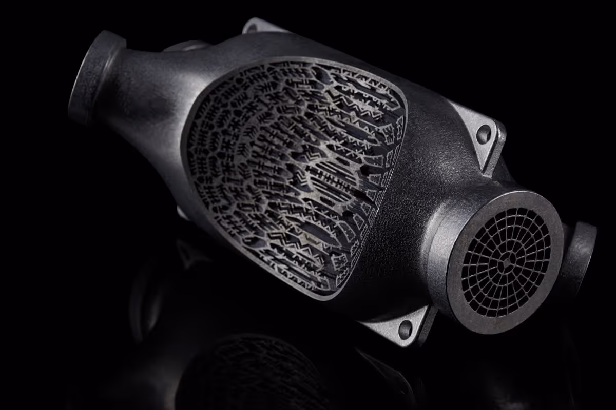 A young woman working in a machine shop. She is looking directly towards the camera, and is surrounded by men.