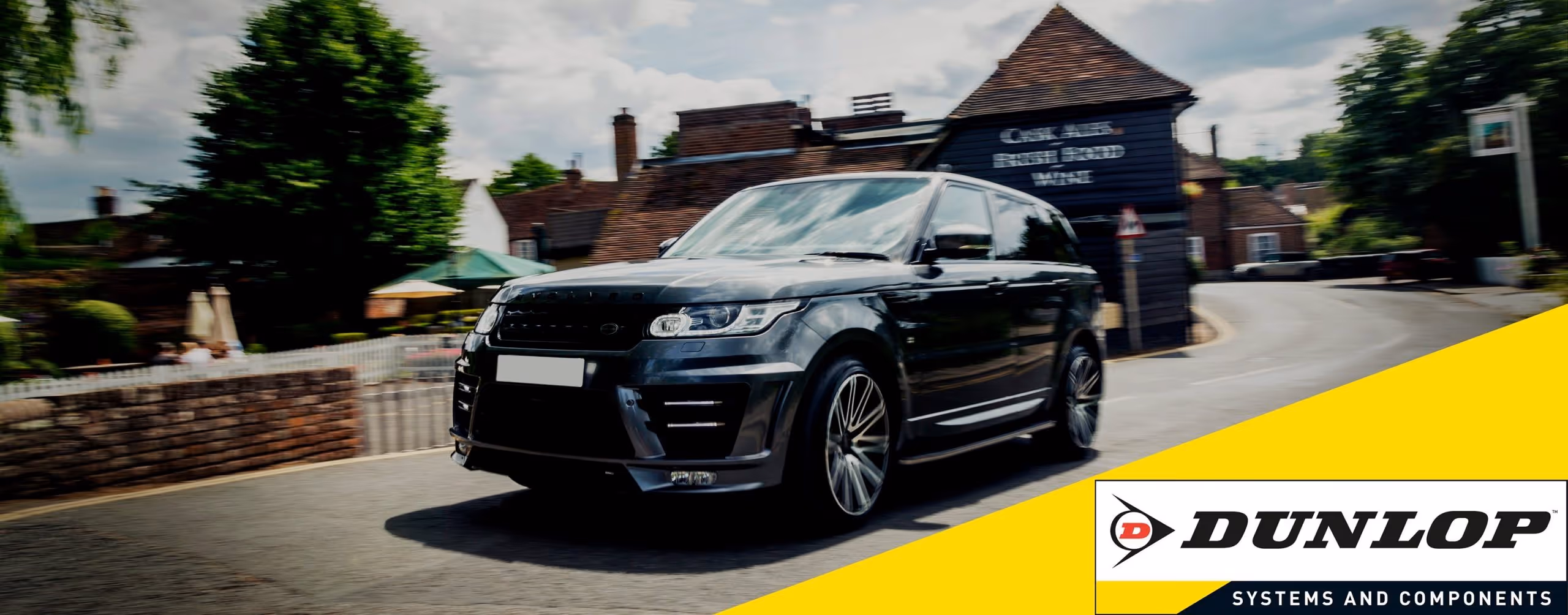 A young woman working in a machine shop. She is looking directly towards the camera, and is surrounded by men.