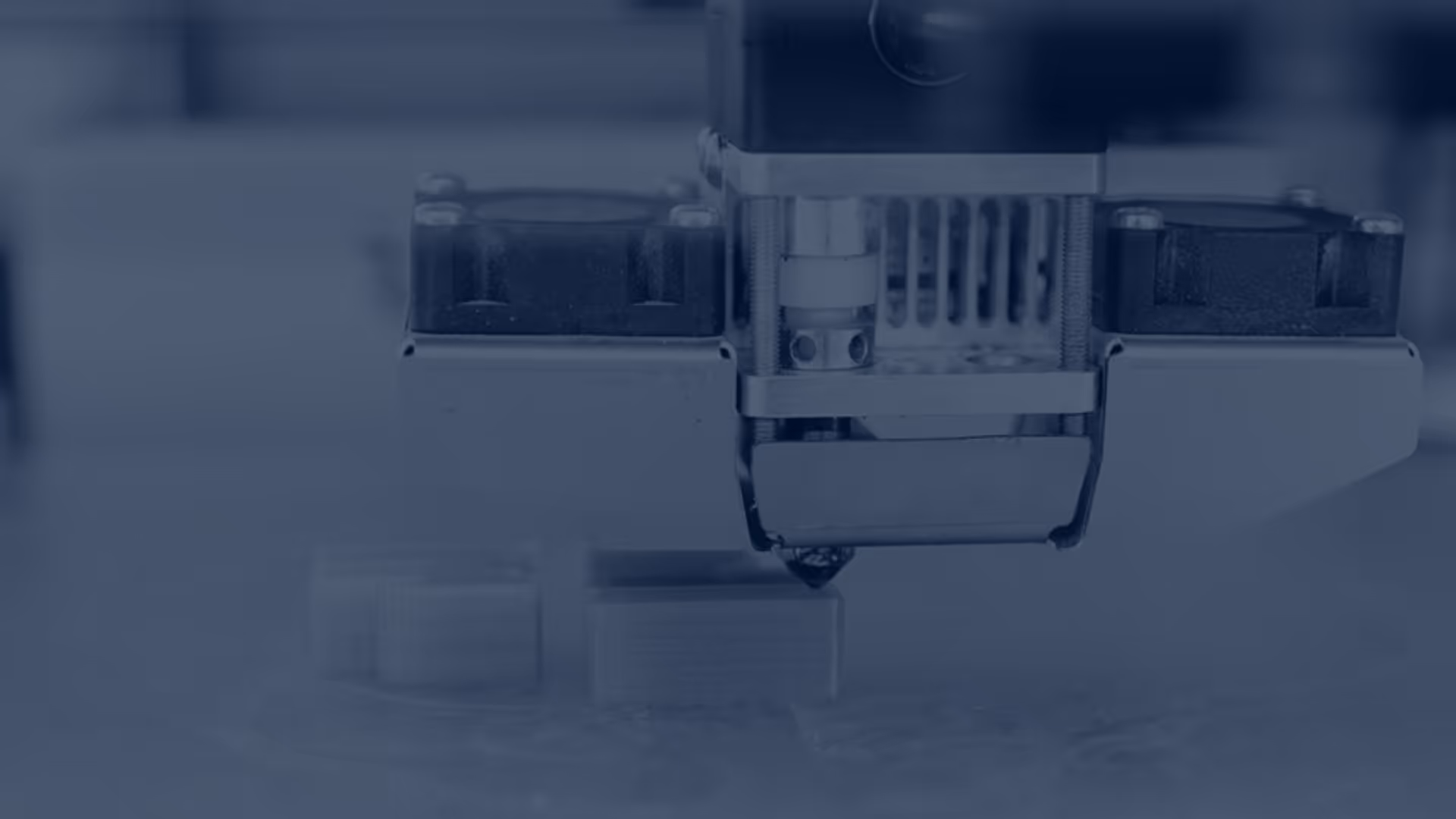 A young woman working in a machine shop. She is looking directly towards the camera, and is surrounded by men.